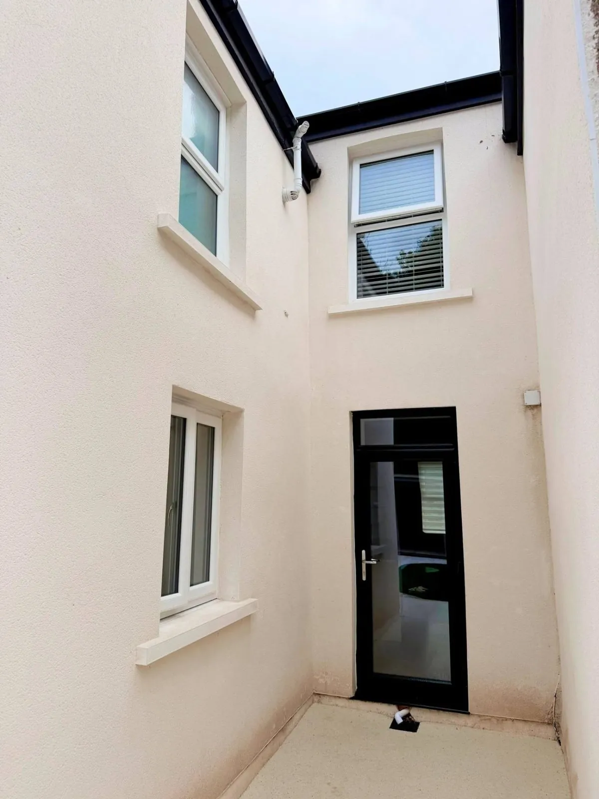 White double glazed windows and black uPVC door in a rendered courtyard