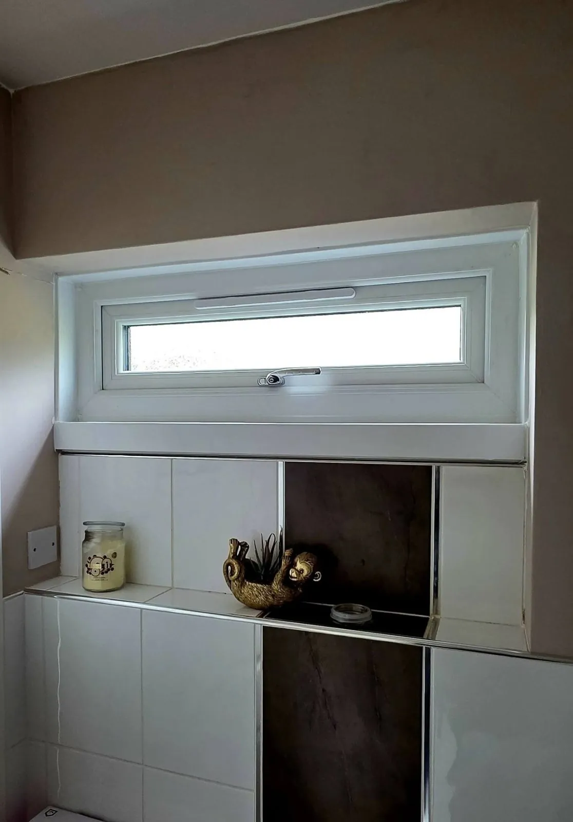 Small white uPVC top opener window above kitchen tiles