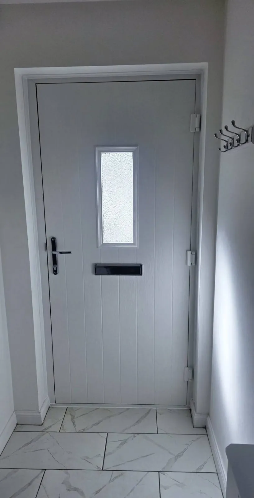 Inside view of a newly fitted composite door with grey frame and tiled floor