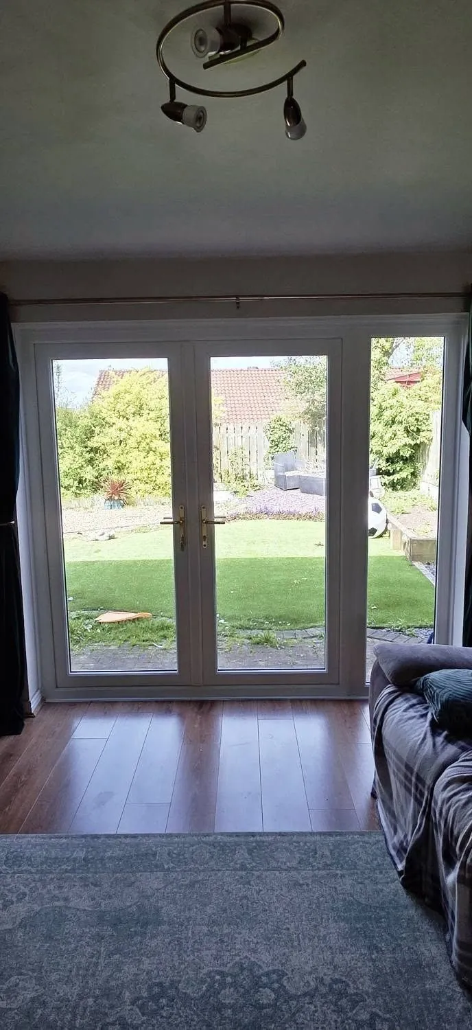 White uPVC French doors opening onto a garden, interior view