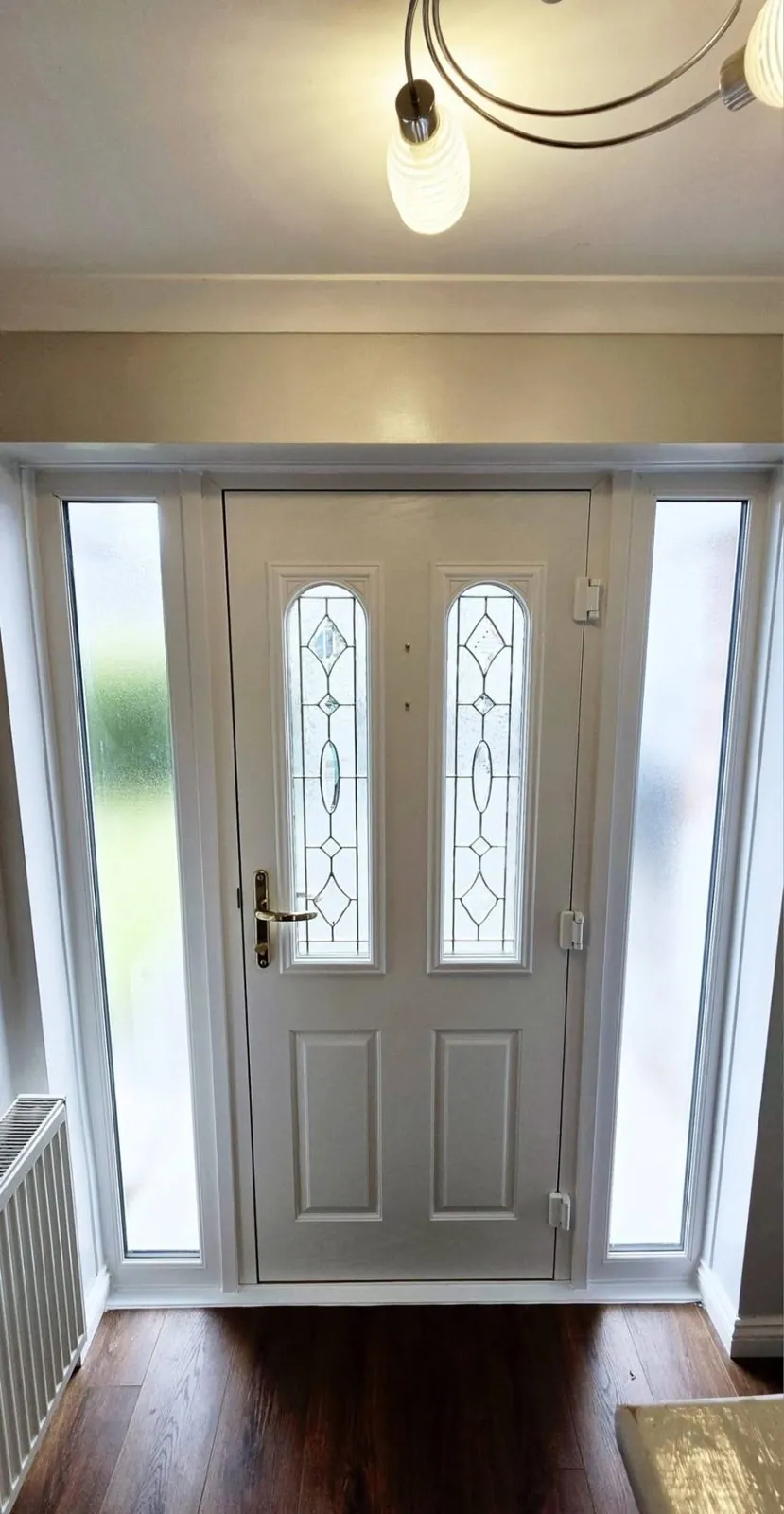 White composite door with decorative glass and side screens, viewed from inside the hallway