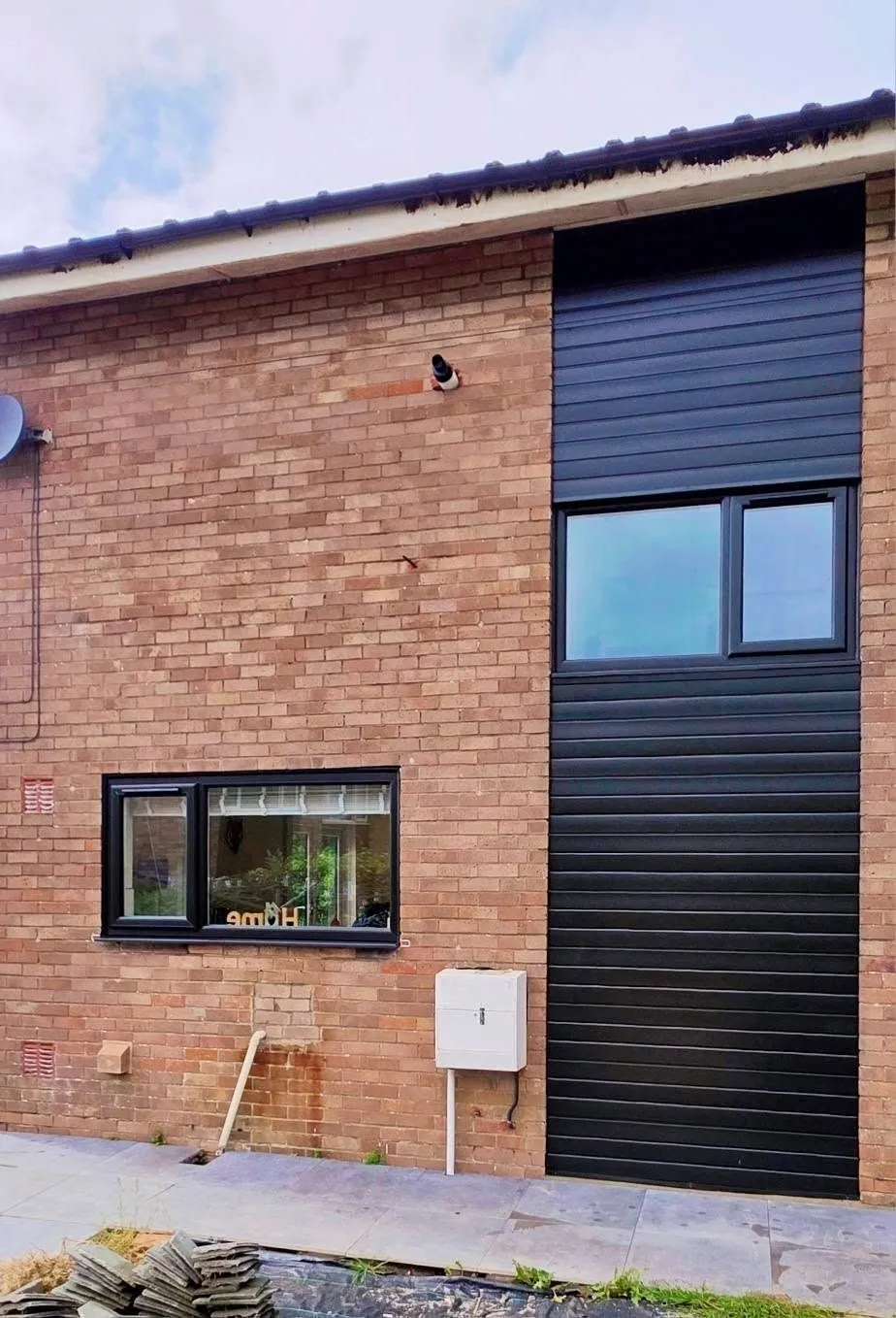 Black uPVC windows fitted to a brick house with black cladding