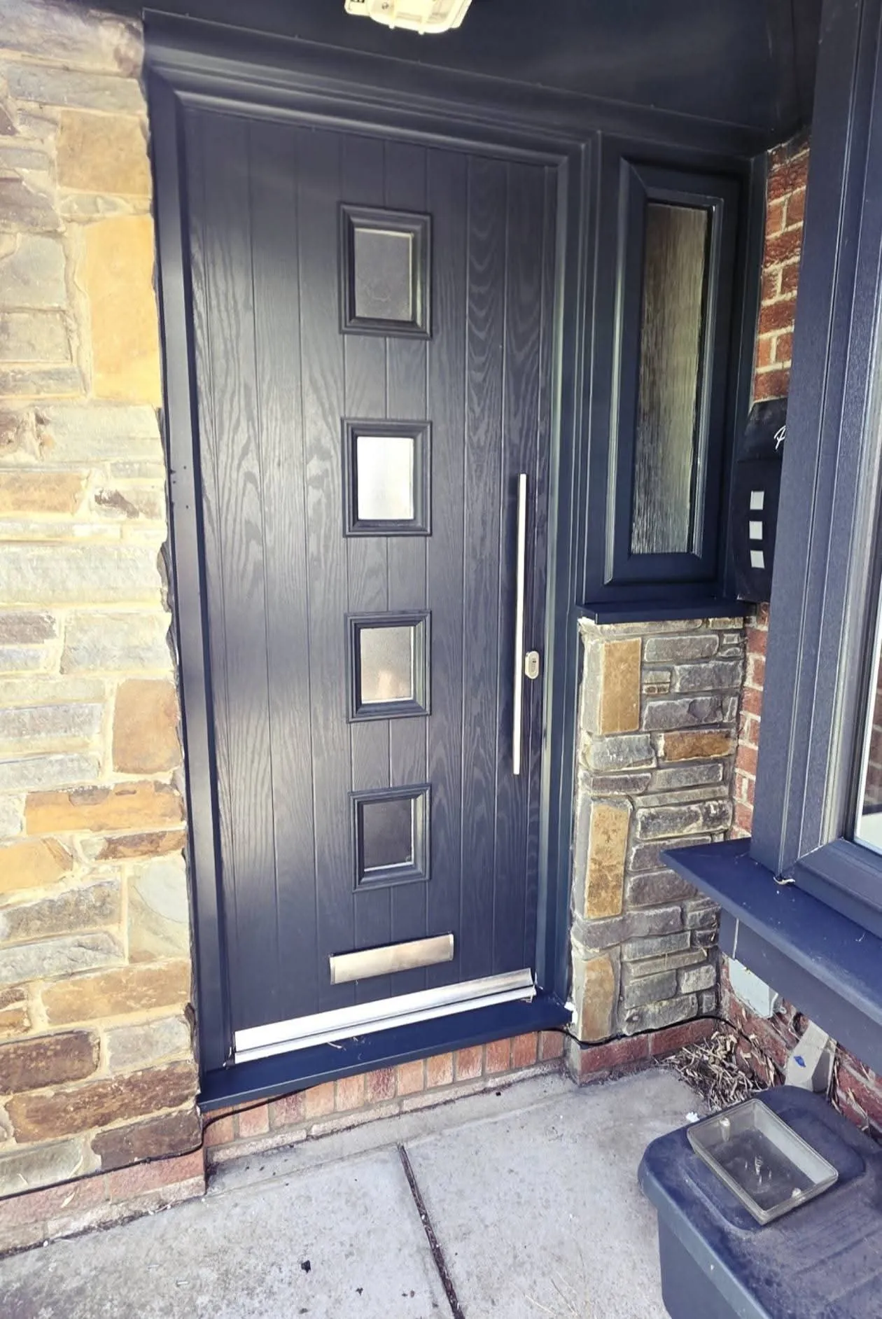 Anthracite grey composite front door with four glass squares, bar handle and side panel