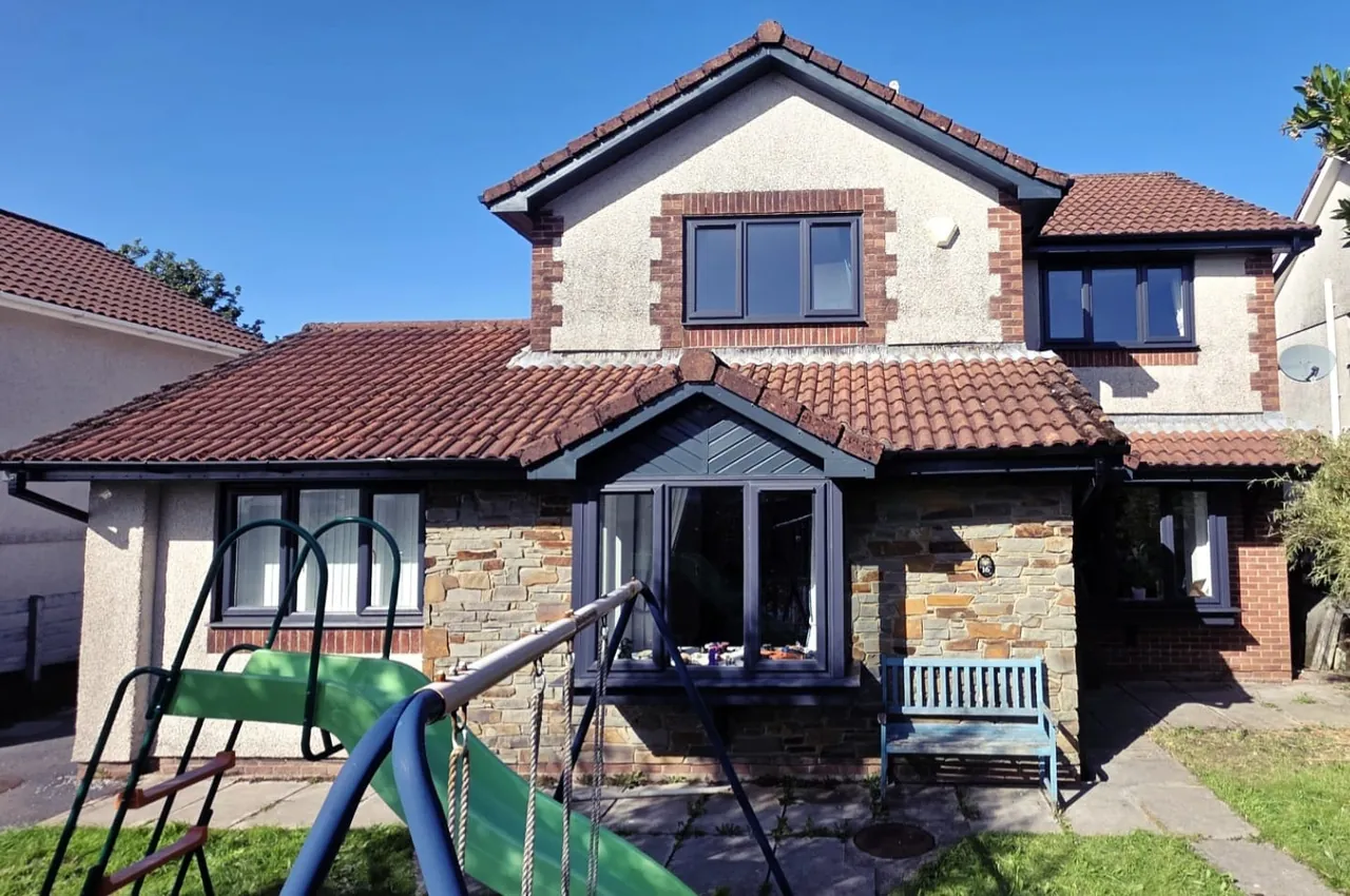 Stone-fronted house with anthracite windows and a grey bay window
